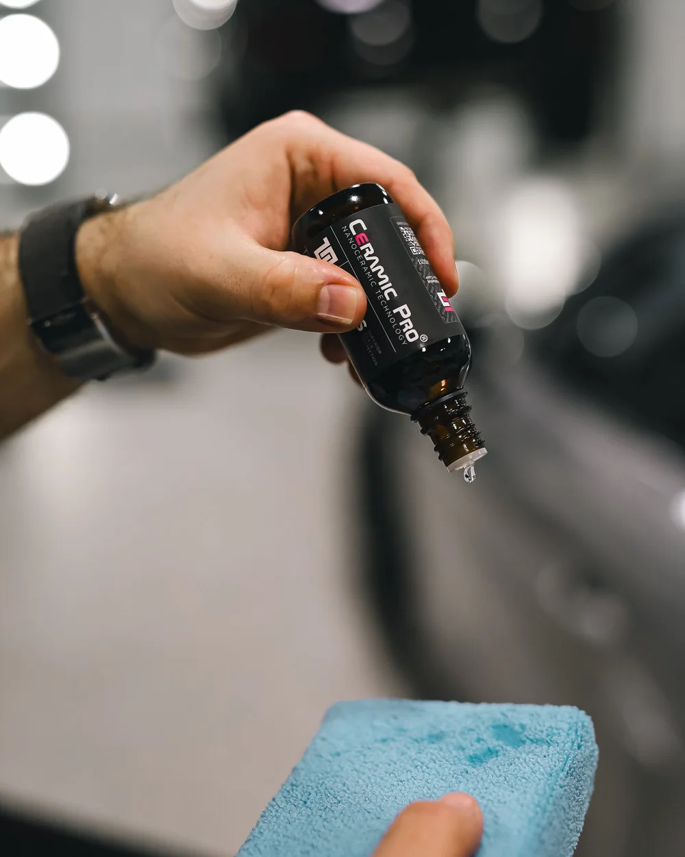 Goutte de revêtement céramique versée sur un applicateur bleu, carrosserie grise derrière